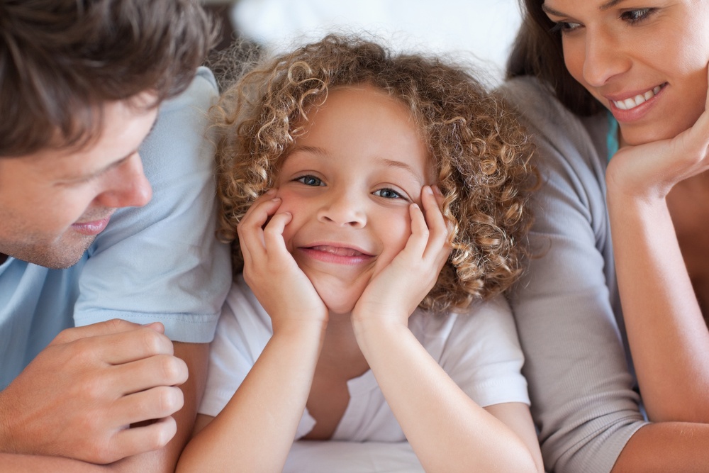 Close up of parents looking at their son while lying on a bed